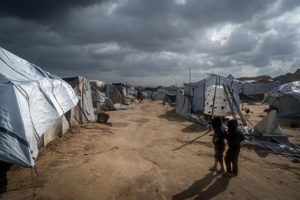 طفلان يسيران عبر ملاجئ بالقرب من ميناء خان يونس في غزة.