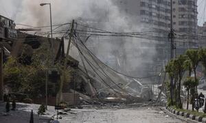 A heavily damaged and collapsed building in Beirut, Lebanon, with smoke rising from the rubble following airstrikes on March 12, 2026.
