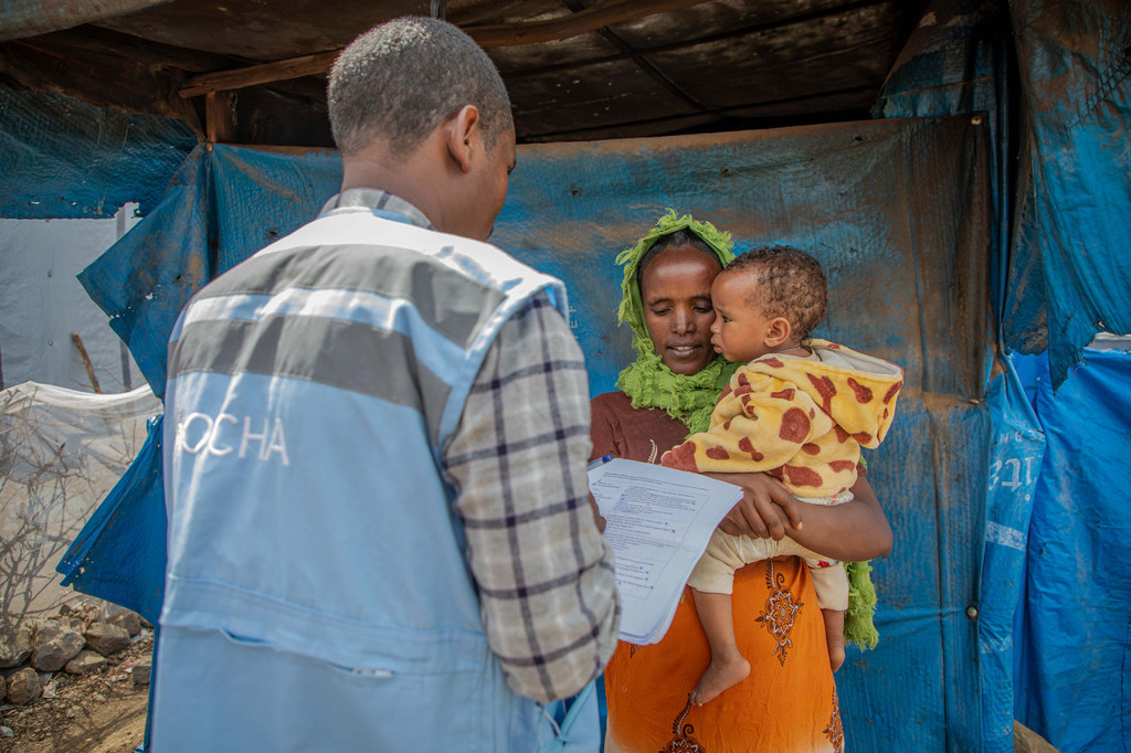 أحد موظفي الأمم المتحدة يتحدث مع والدة طفل يعاني من سوء التغذية في موقع لإيواء النازحين في ميكيلي، في منطقة تيغراي شمال إثيوبيا.