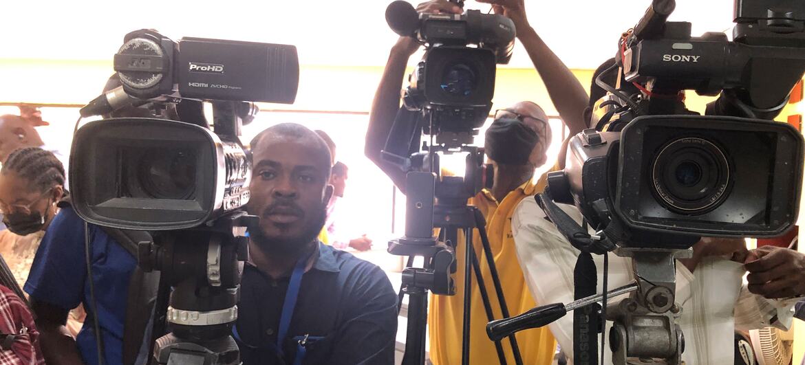 Um grupo de cinegrafistas com câmeras de vídeo profissionais em tripés em um evento de imprensa no Haiti.