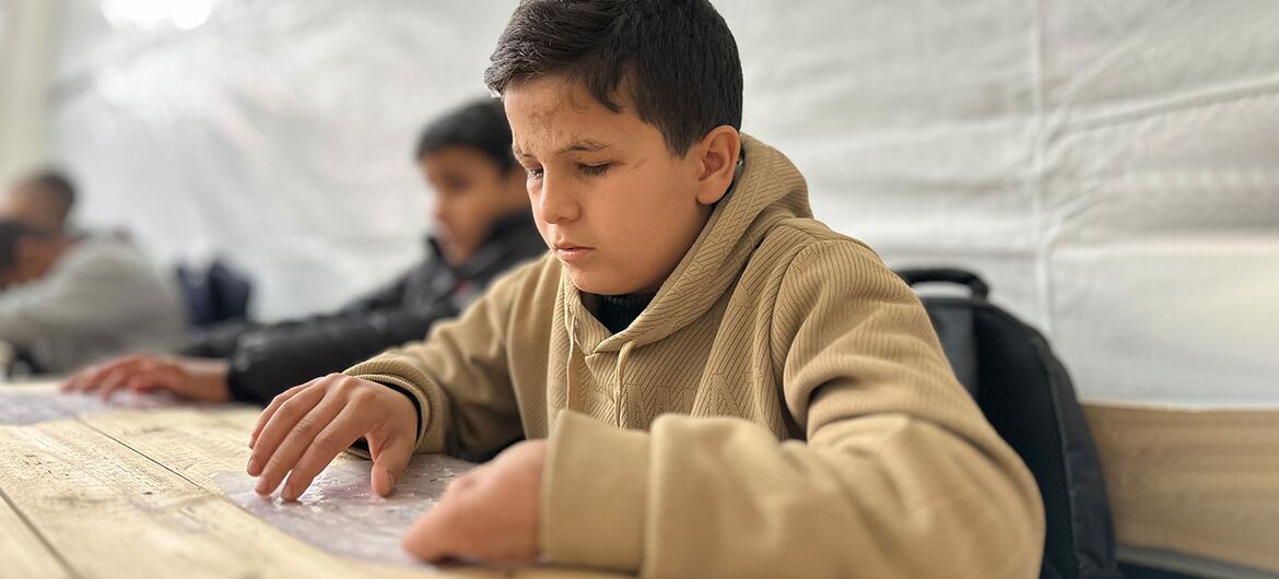 Fourteen-year-old Mohammed, a Palestinian student with visual impairment, concentrates on learning Braille at the Rehabilitation Centre for Visually Impaired Children in Gaza, supported by UNRWA.