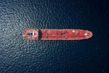 Aerial view of a red oil tanker ship in the open ocean.