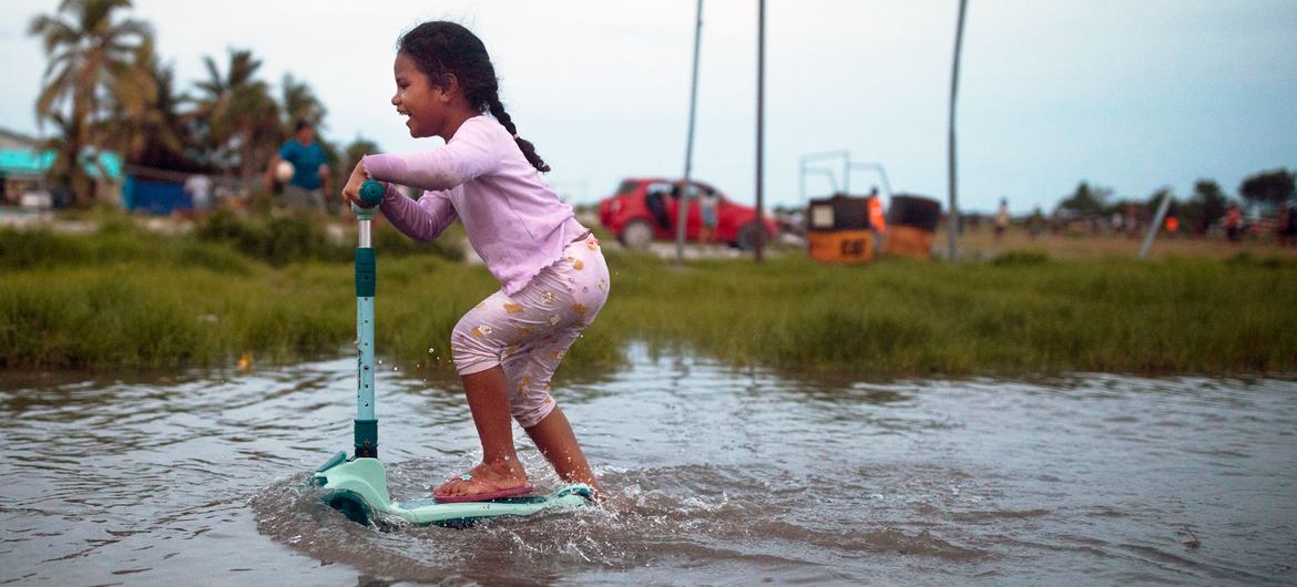 A small child scoots through flooded terrain in Tuvalu in the Pacific Ocean.