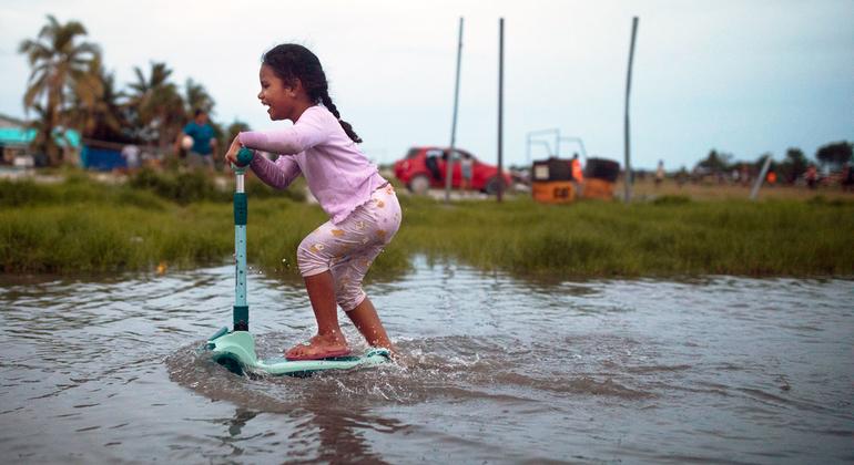 A small child scoots through flooded terrain in Tuvalu in the Pacific Ocean. A small child scoots through flooded terrain in Tuvalu in the Pacific Ocean.