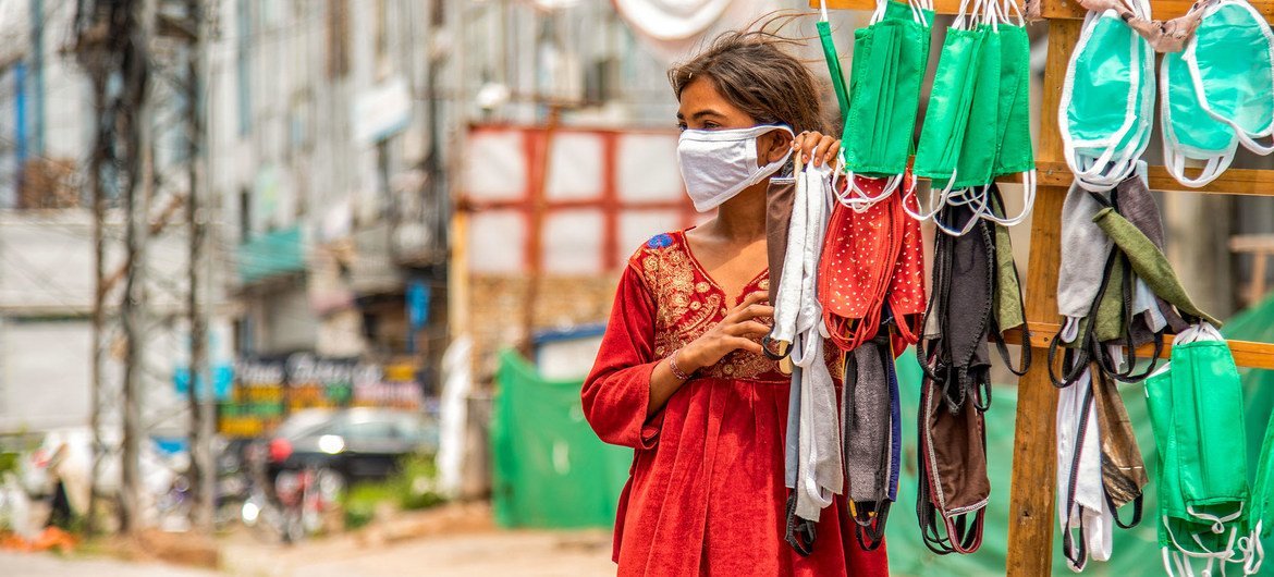 پاکستان میں ایک لڑکی سڑک کنارے ماسک بیچ رہی ہے۔
