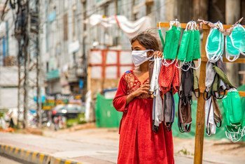 پاکستان میں ایک لڑکی سڑک کنارے ماسک بیچ رہی ہے۔