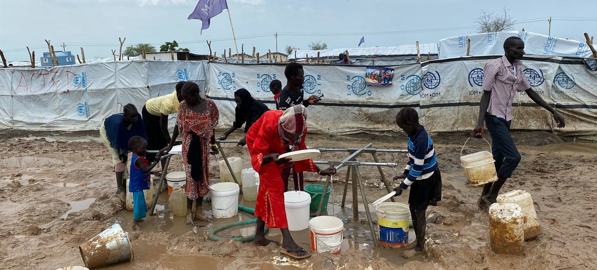 Le persone che vivono in un campo temporaneo a Renk raccolgono l'acqua.