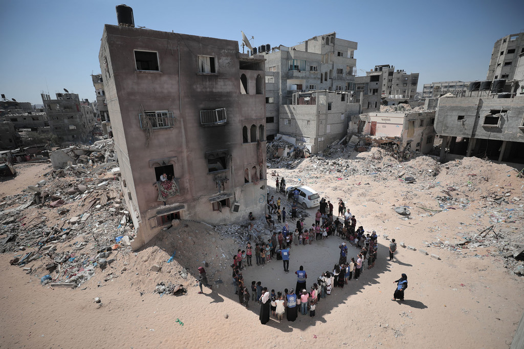 Children find shade and take part in recreational activities organized by UN personnel in front of destroyed buildings in the Gaza Strip.