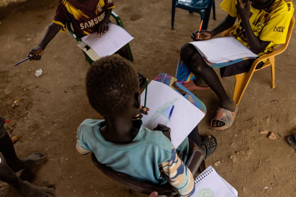 Des enfants dessinent dans un espace adapté aux enfants soutenu par l'UNICEF dans un camp du Darfour Sud, au Soudan, pour les personnes déplacées par le conflit.