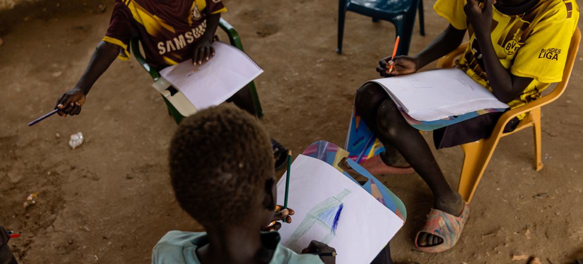 Crianças desenham em um espaço amigável para crianças apoiado pelo UNICEF em um acampamento no sul de Darfur, no Sudão, para pessoas deslocadas pelo conflito.