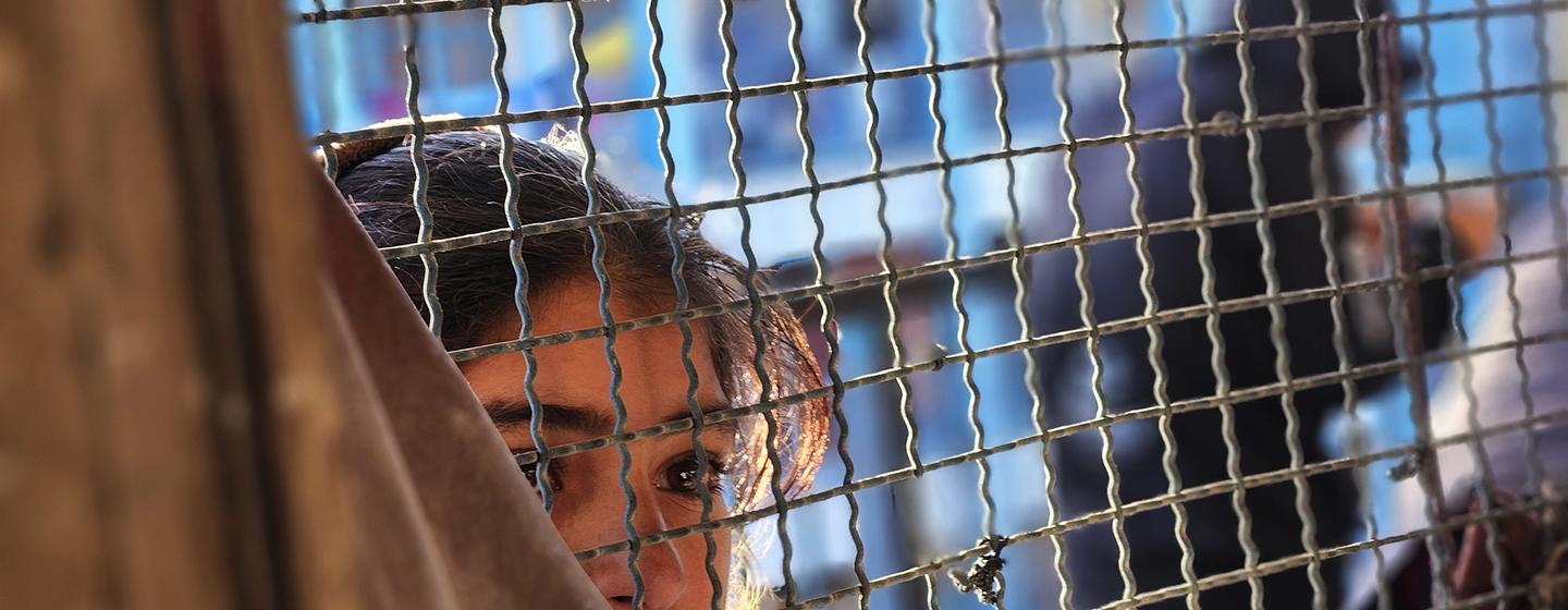 Une jeune fille regarde à travers une fenêtre à Khan Younis, Gaza.