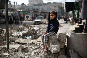 在加沙地带南部的拉法，一名 11 岁的女孩坐在一座房子的废墟上。