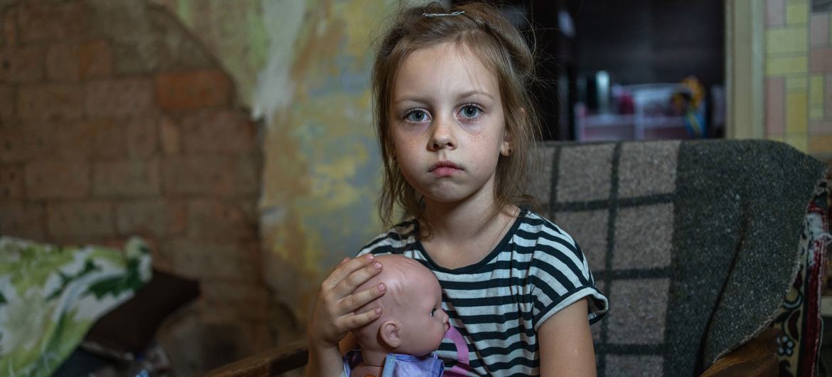 Milana, de sete anos, segura sua querida boneca, Omelka, perto do peito no pequeno quarto que sua família agora divide depois de fugir de Myrnohrad, na região de Donetsk, na Ucrânia.