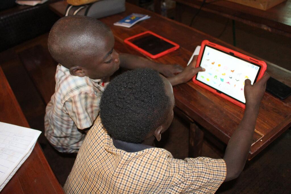 Deux jeunes garçons en Tanzanie apprennent à l'aide d'une tablette dans une classe.