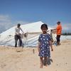 一个女孩在玩耍，而她的家人正在加沙地带南部拉法的营地架设一个新帐篷。