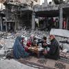 Uma família em Gaza faz uma refeição entre os escombros de sua casa.