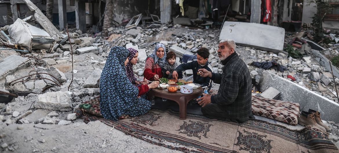 A family in Gaza eats a meal in the midst of the rubble of their home.