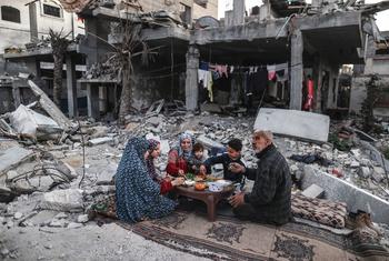 A family in Gaza eats a meal amongst the rubble of their home.
