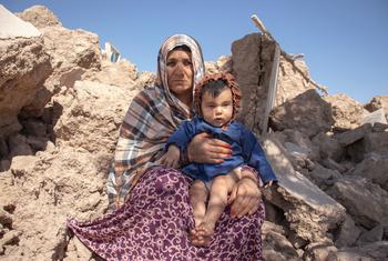 Una mujer sostiene a un niño de 6 meses sentada entre los escombros de las casas destruidas por un terremoto en Afganistán.