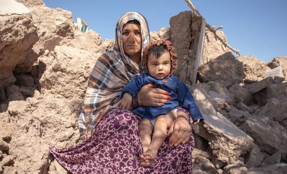 A woman holds a 6-month-old child while sitting in rubble of homes in Afghanistan which were destroyed by an earthquake.