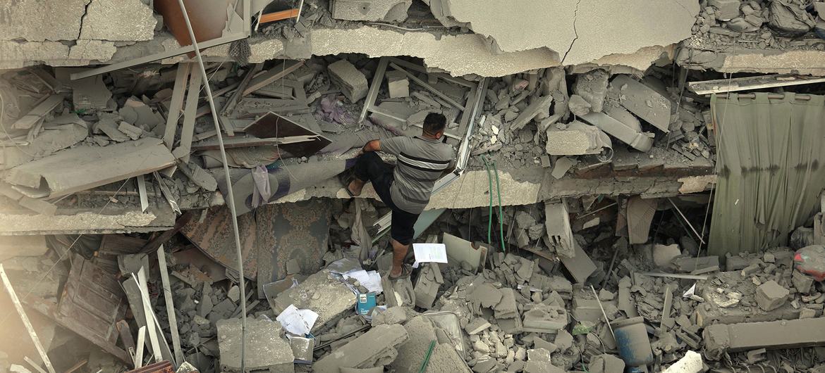 Un hombre camina por encima de los escombros de un edifico destruido en Gaza.