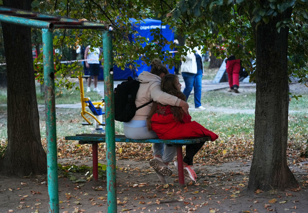 Женщина обнимает дочь возле жилого дома, пораженного ракетами в Киеве.