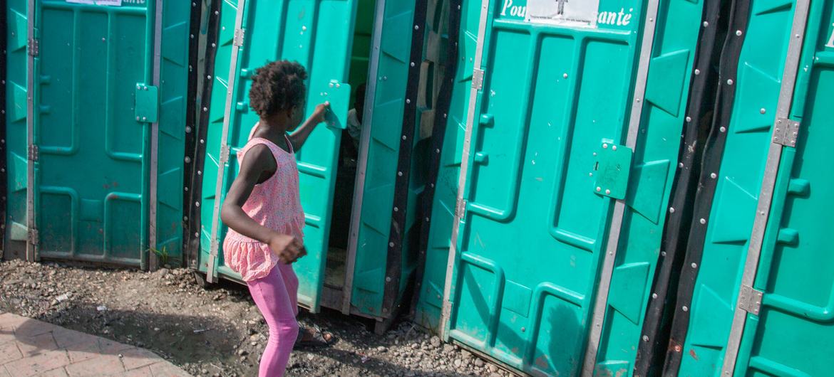 A young girl uses a portable toilet at a site for people displaced by inter-gang violence.