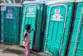A young girl uses a portable toilet at a site for people displaced by inter-gang violence.
