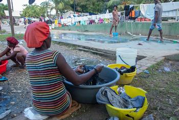 在海地首都太子港，一名因暴力而流离失所的妇女在城市公园洗衣服。
