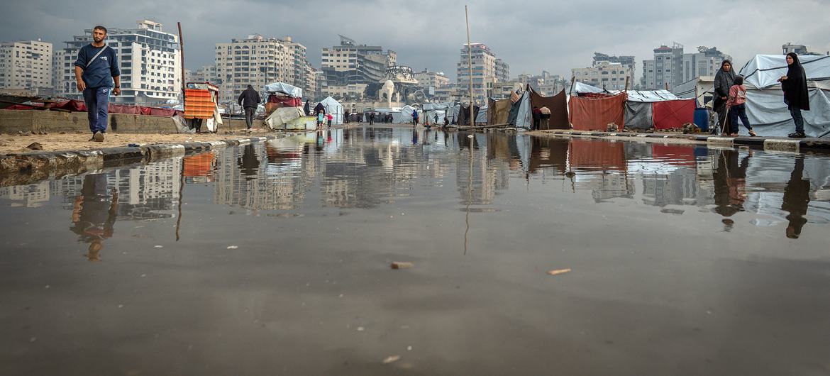 People in Gaza walk past a puddle of water following heavy rain.