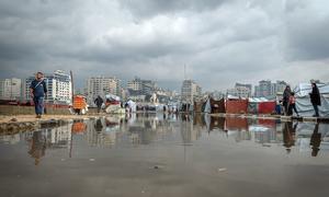 People in Gaza walk past a puddle of water following heavy rain.