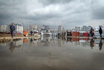 La gente en Gaza camina junto a un charco de agua tras las fuertes lluvias.