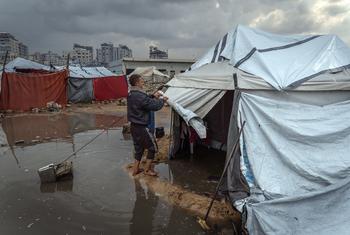 رجل يصلح خيمته بعد هطول أمطار غزيرة في غزة.