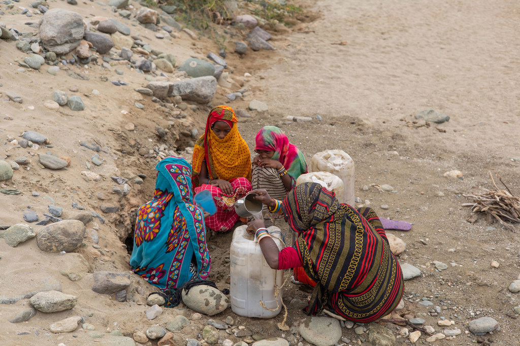 सूडान में अगिग इलाके में महिलाएं और बच्चे एक असुरक्षित स्रोत से पानी इकट्ठा कर रहे हैं।