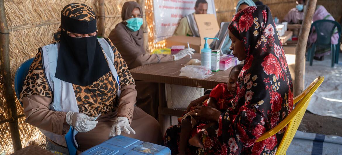 A woman holds a child while receiving medical care at a UNICEF-supported health center in Sudan's Kordofan region, where families have fled violence.