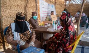 A woman holds a child while receiving medical care at a UNICEF-supported health center in Sudan's Kordofan region, where families have fled violence.
