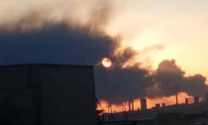 Sunset behind thick industrial smoke rising over the Tehran city skyline in Iran.