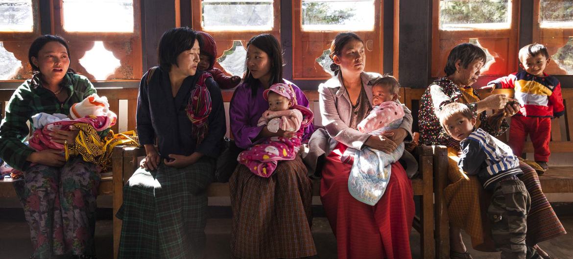 Madres y sus bebés esperan para ver a los trabajadores sanitarios apoyados por la ONU en Bután.