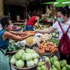 A vegetable vendor serves a customer at a market in Manila, Philippines.