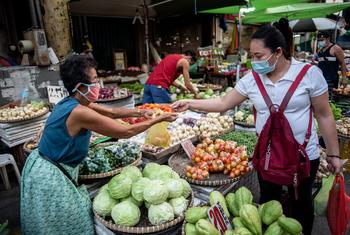 A vegetable vendor serves a customer at a market in Manila, Philippines.