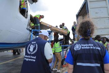 Trabajadores descargan cajas de suministros médicos de emergencia de un avión de carga en un aeropuerto de Bunia, República Democrática del Congo, para apoyar la respuesta al ébola. Los trabajadores visten chalecos del Programa Mundial de Alimentos y la OMS.
