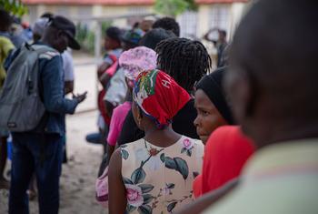 Pessoas de uma comunidade afetada pela violência de gangues em Porto Príncipe fazem fila para comprar comida