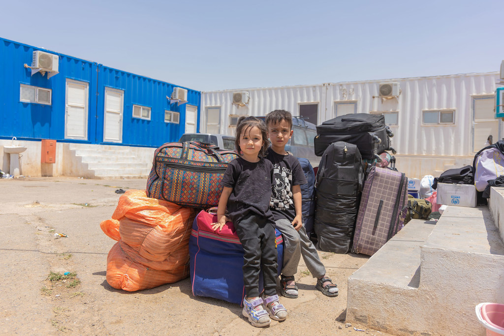 Watoto wawili wadogo wameketi karibu na mali ya familia yao kwenye kivuko cha mpaka cha Islam-Qala, saa chache baada ya kurejea Afghanistan.