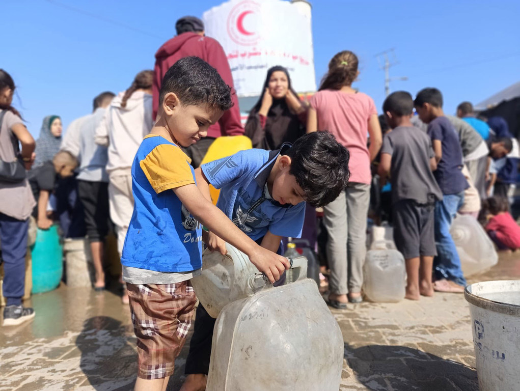 Young boys fill water containers in Gaza.