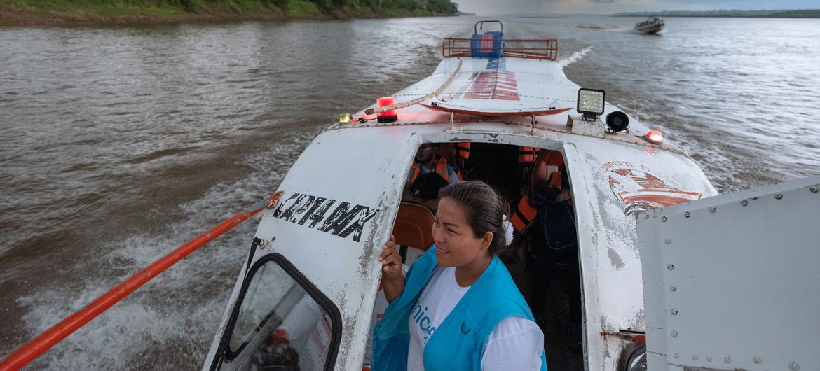 Gissela Vasquez, a nursing technician and community liaison worker, looks out from the doorway of a boat traveling on the Tigre River in Loreto, Peru.