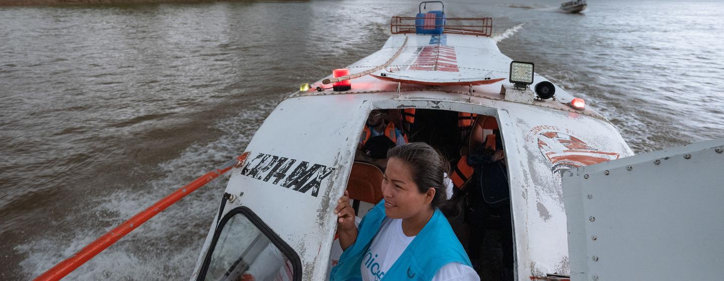 Gissela Vásquez, técnica de enfermería y trabajadora de enlace comunitario, mira desde la puerta de una embarcación que navega por el río Tigre en Loreto, Perú.