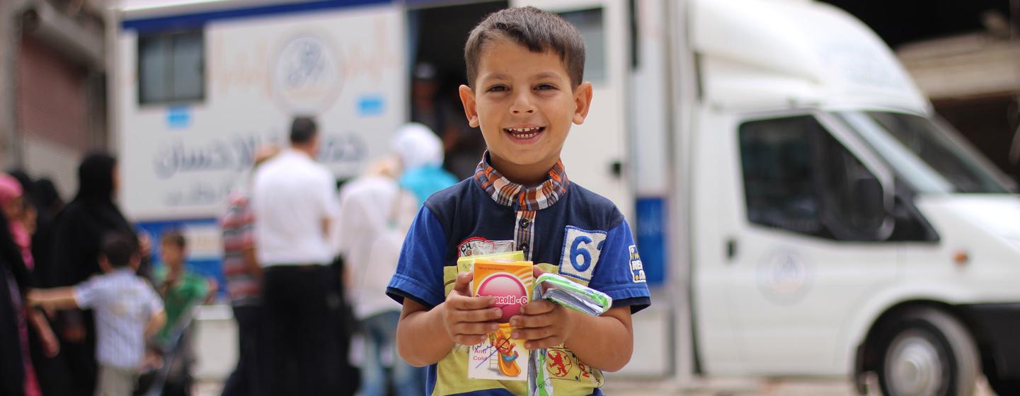 Un enfant tient dans ses mains des médicaments qu'il a reçus d'agents de santé dans une clinique mobile dans un quartier de l'est d'Alep, en Syrie.