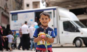 在叙利亚阿勒颇，一名儿童从移动诊所获得药物。