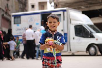 Un enfant tient dans ses mains des médicaments qu'il a reçus d'agents de santé dans une clinique mobile dans un quartier de l'est d'Alep, en Syrie.