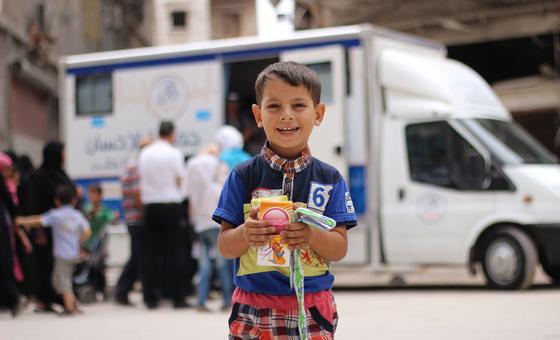 Un enfant tient dans ses mains des médicaments qu'il a reçus d'agents de santé dans une clinique mobile dans un quartier de l'est d'Alep, en Syrie.
